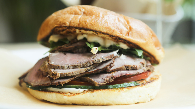 A close-up shot of a freshly made roast beef sandwich with dressing and veggies