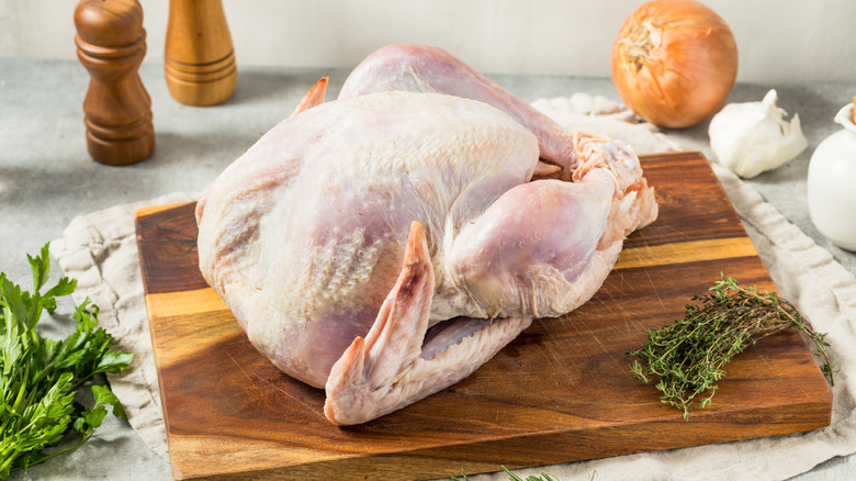 Whole raw turkey on a wooden cutting board