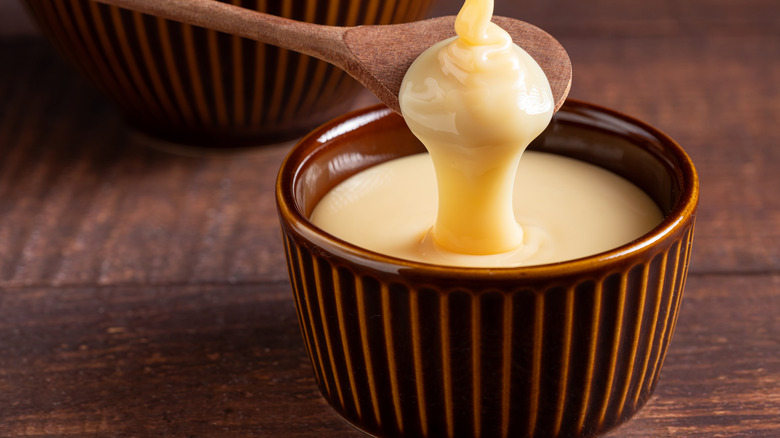 closeup of condensed milk in ramekin with wooden spoon