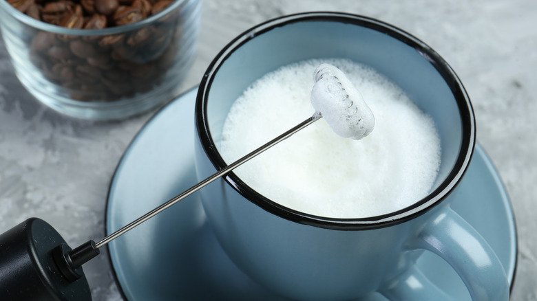 closeup of electric milk frother over mug
