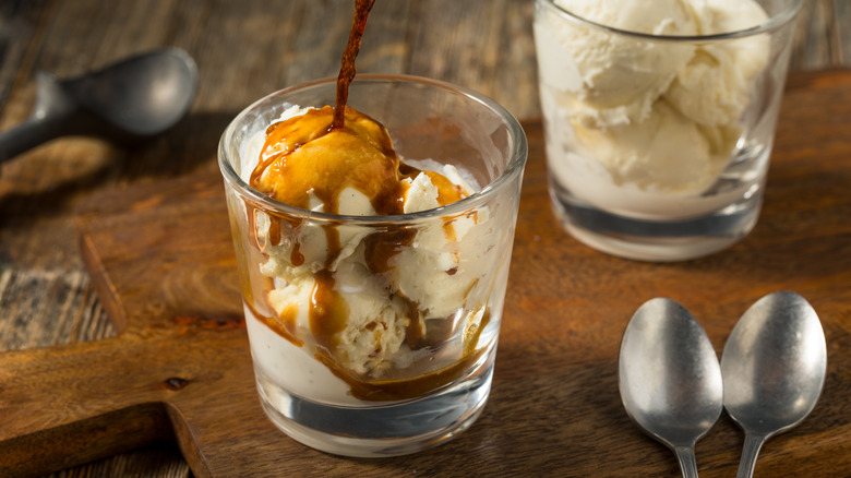 espresso being poured over vanilla ice cream in clear glass on wooden surface