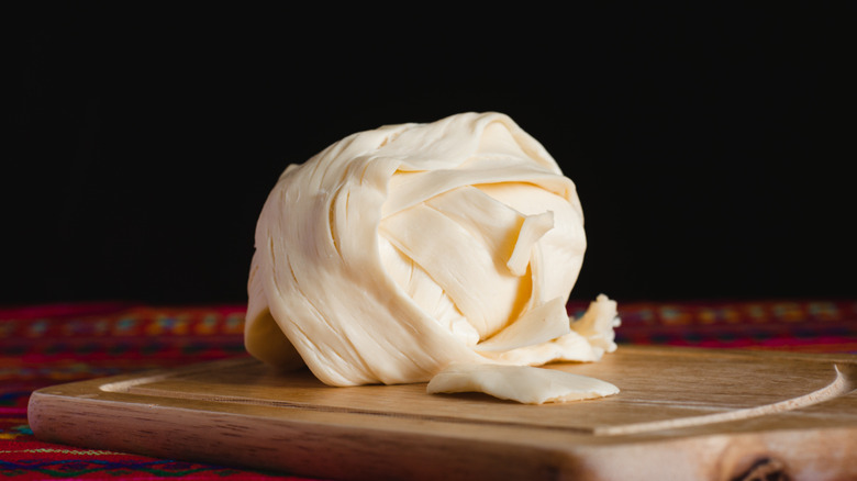 closeup of oaxaca cheese ball on wooden cutting board