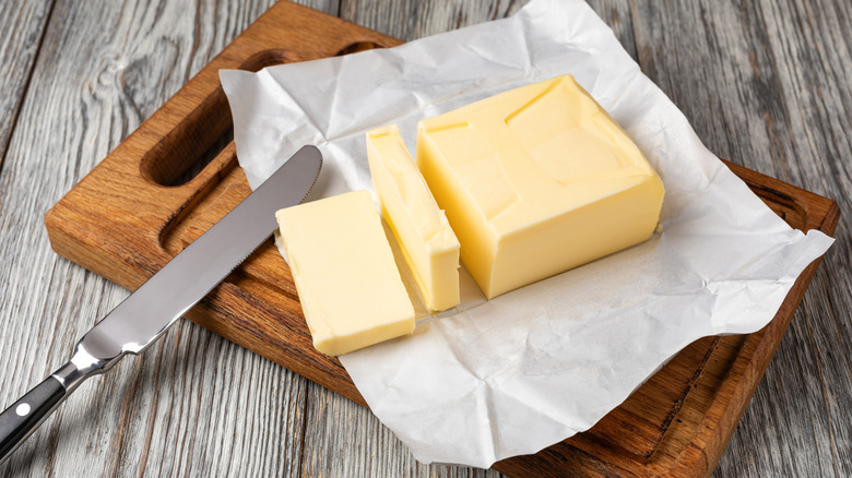 fresh sliced butter on wooden cutting board with knife