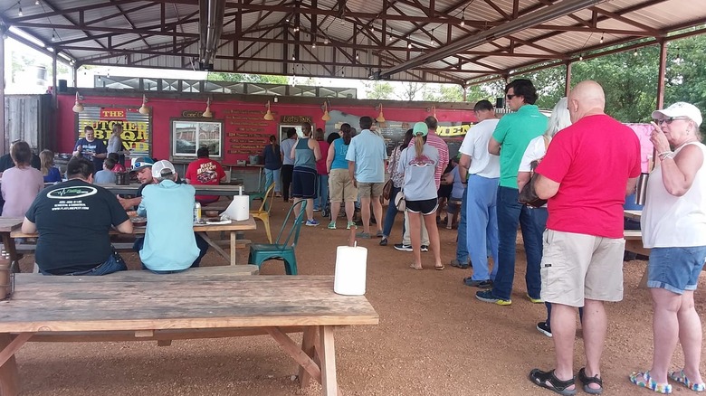 A line of people at a red bbq trailer