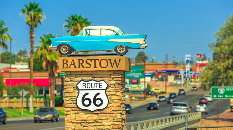 A blue 1950s style model car on a Route 66 sign entering Barstow