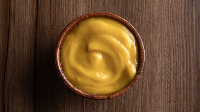 A bowl of yellow mustard on a counter
