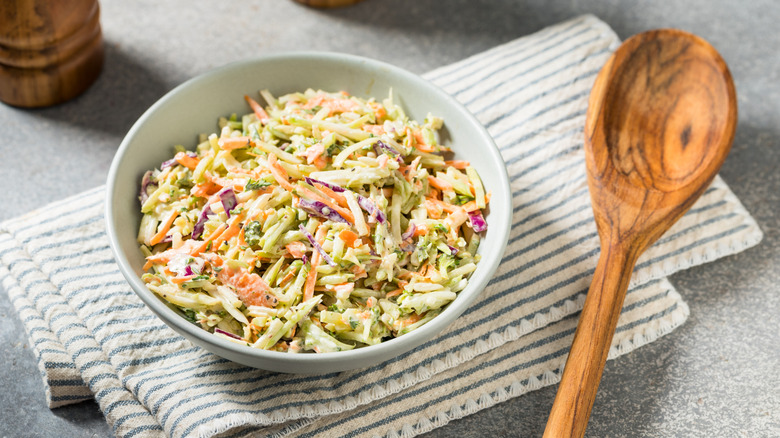 A bowl of coleslaw on a folded rag with a spoon