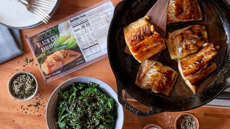 Trader Joe's miso black cod cooked in a pan next to veggies and box of black cod sablefish