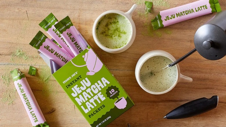 Trader Joe's instant matcha packets spilled out of opened box next to two cups of lattes