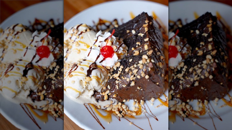 A slice of chocolate cake on a plate with cream and a cherry