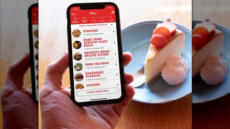 Hand holding a phone with the Logan's Roadhouse app open in front of a plate of cheesecake and cream