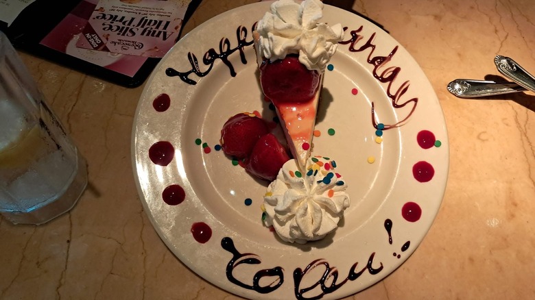 A slice of cheesecake with a happy birthday message at The Cheesecake Factory