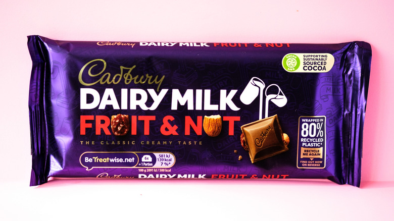 A bar of Cadbury Dairy Milk Fruit and Nut Chocolate against a light pink background.