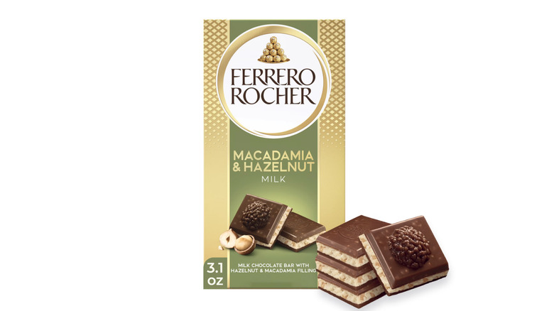 A Ferrero Rocher Macadamia and Hazelnut Milk chocolate bar and four squares of chocolate on a white background