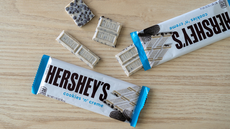 Wrapped Hershey's Cookies 'n' Creme candy bars and pieces of white chocolate on lightly colored wood table