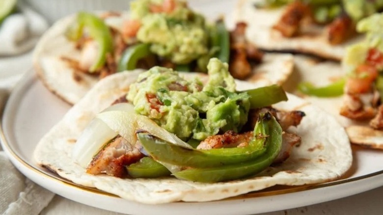 Grilled chicken fajitas inside flour tortillas, topped with guacamole