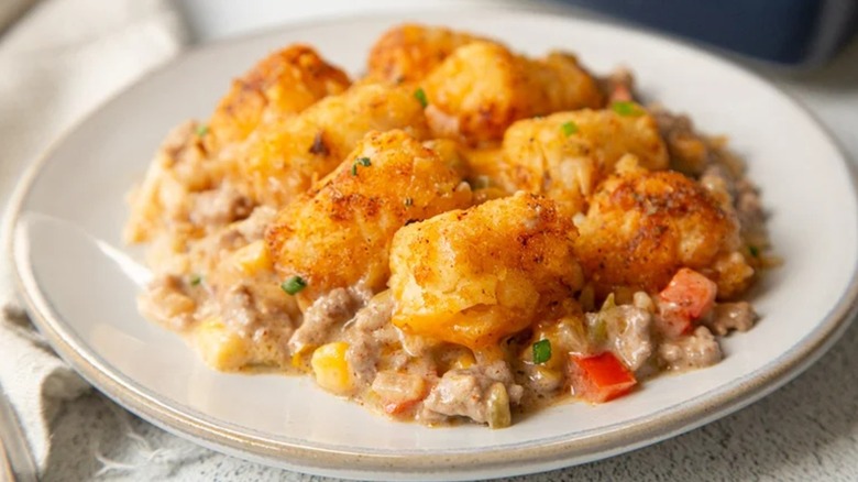 A plate of cowboy casserole with ground beef, cream of mushroom soup, vegetables, and tater tots