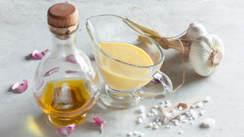 pouring vessel with aioli alongside garlic, oil, and salt