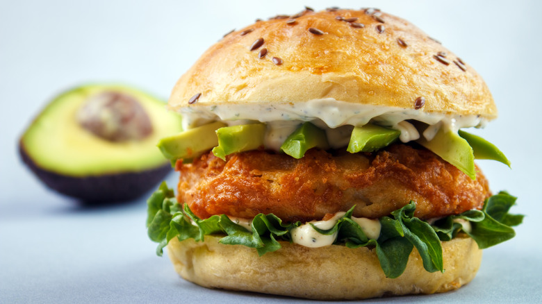 avocado fish sandwich with half avocado in background
