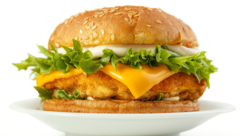 fish burger with lettuce, mayo, and cheese on white plate
