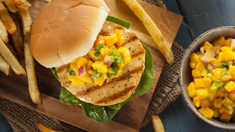 mango salsa on fish sandwich alongside mango salsa bowl and fries