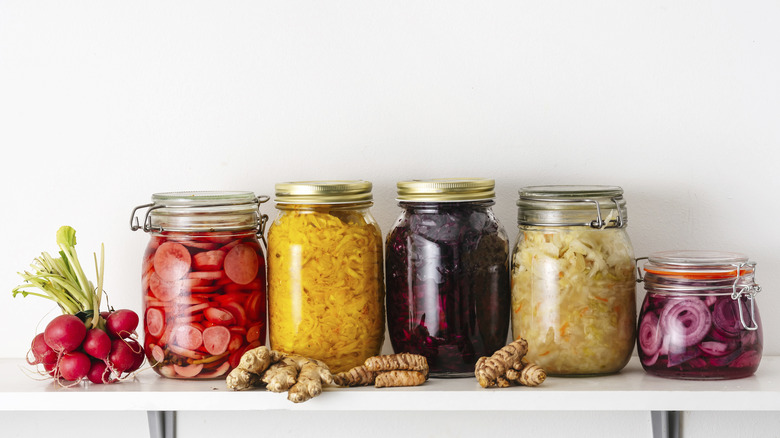 line of colorful pickled veggies in glass jars