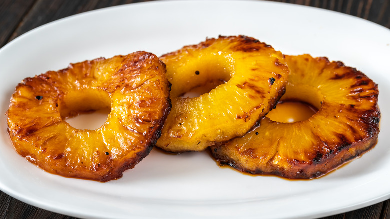 three caramelized pineapple rings on white plate