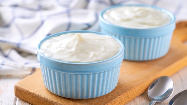 two blue ramekins of sour cream on wooden cutting boards