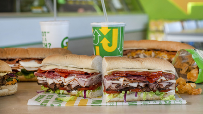 Assorted Subway foot long sandwiches, drinks, and potato chips