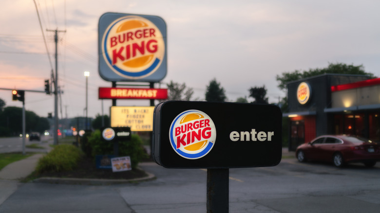 A Burger King restaurant sign with BREAKFAST below it, and, in front of it, an Enter sign in the dim pink light of early morning