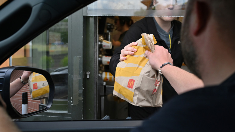 A customer picking up a McDonald's bag from a drive-thru window.