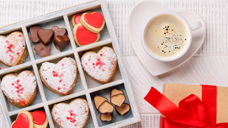 Box of Valentine's Day cookies and and a cup of coffee on heart-shaped saucer