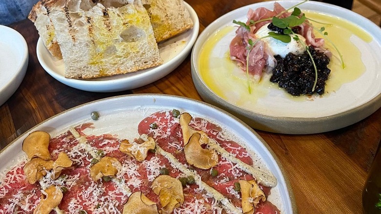 Appetizer plates of carpaccio and bread on a dining table