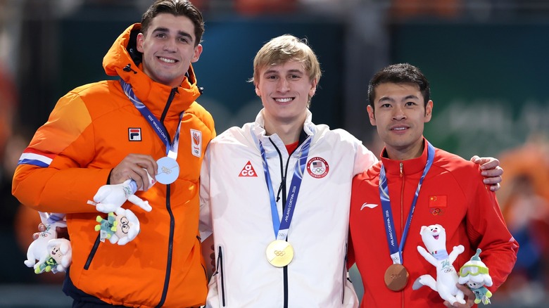 Three Olympians wear gold, silver, and bronze medals