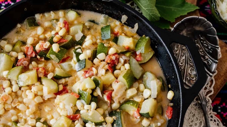 A close-up of a corn and zucchini stew in a cast iron pan