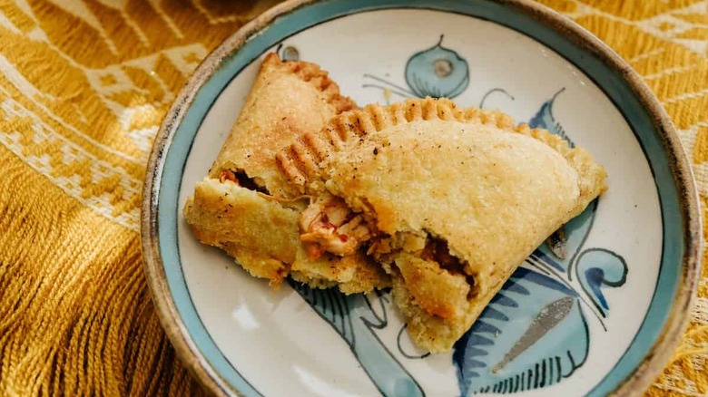 Fried empanada broken into two pieces with the filling showing