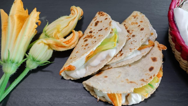 Three quesadillas filled with zucchini blossoms and crema