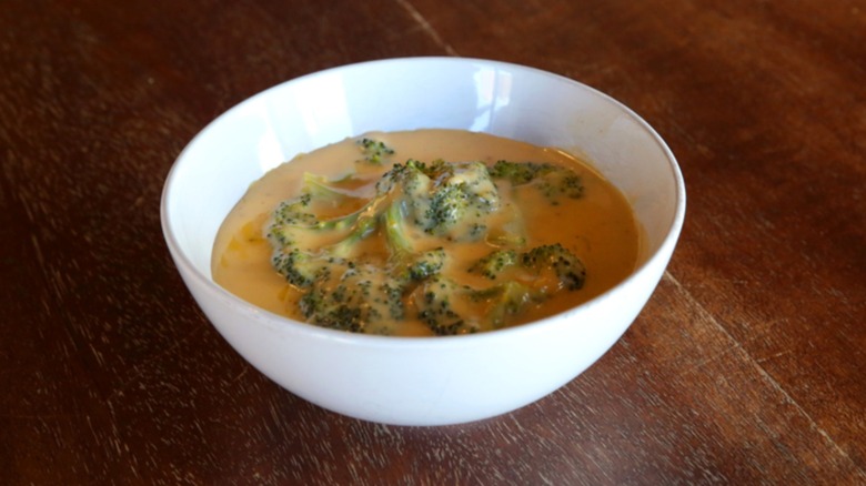 White bowl of broccoli and cheddar soup on table