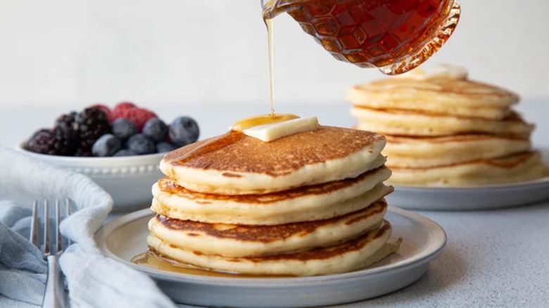 Syrup pouring onto stack of pancakes on plate
