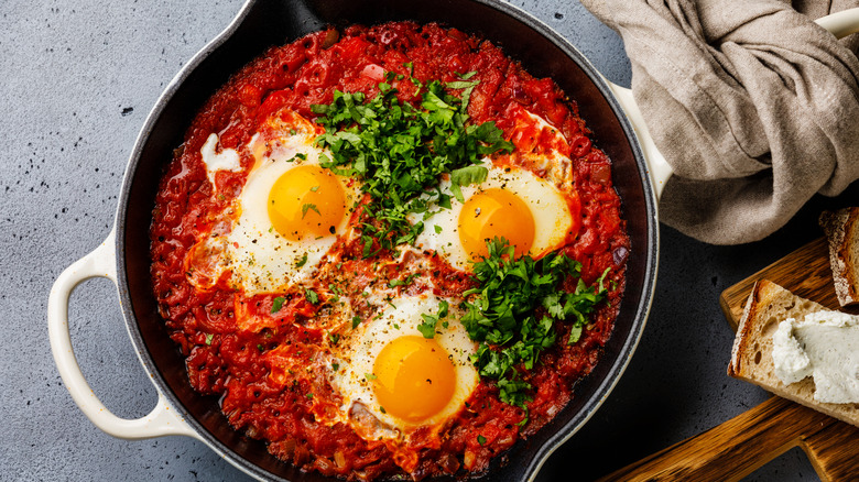 Pan of shakshuka with bread and towel to the side