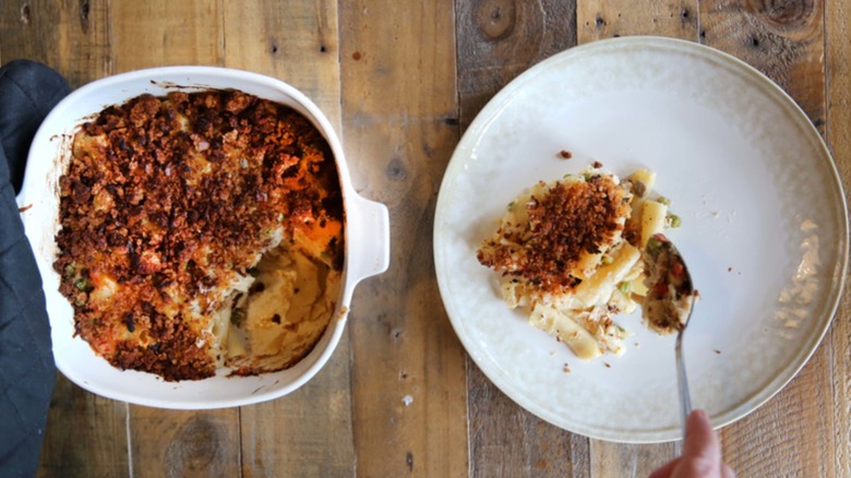 Tuna casserole in dish and being dished out with spoon on another plate