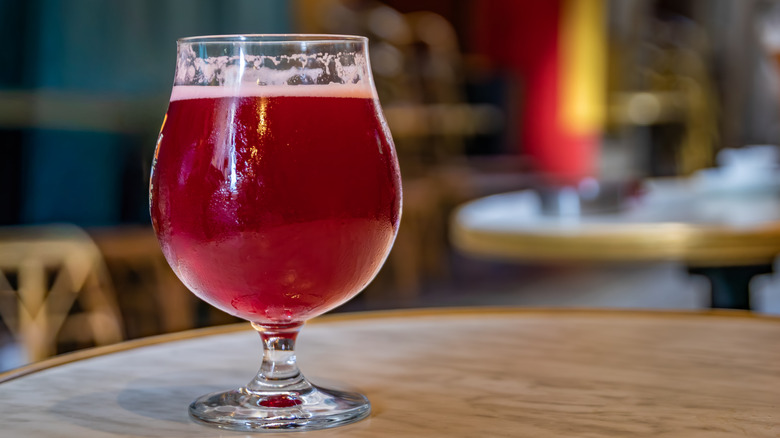 A tulip glass of fruit lambic on a table