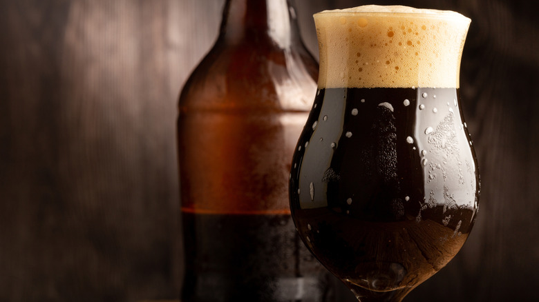 A glass of porter in front of a partially emptied beer bottle