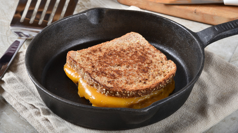 Grilled cheese sandwich in cast iron skillet sitting on a dish rag.