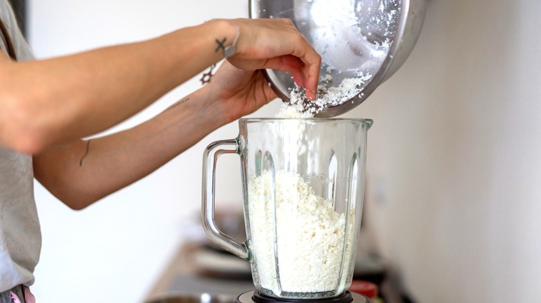A woman pours a bowl of cottage cheese into a blender