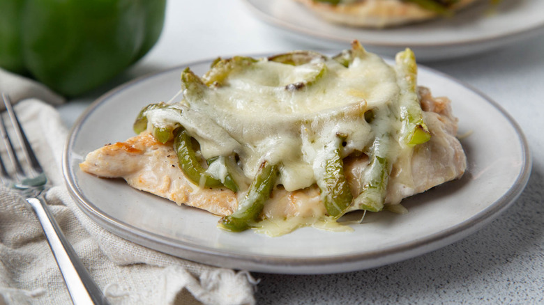 chicken with cheese and green peppers on a white plate