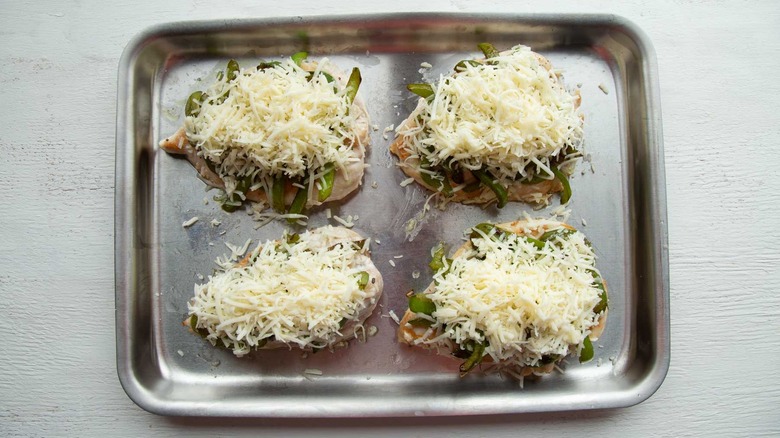 cooked chicken breasts and  shredded cheese in a baking pan