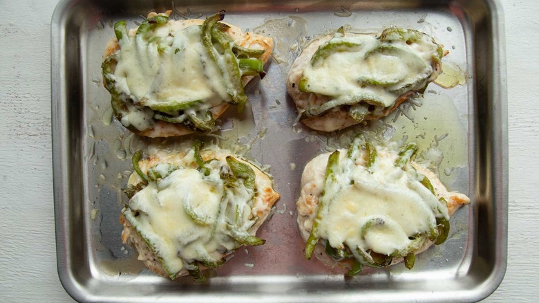 cooked chicken breasts and melted cheese in a baking pan
