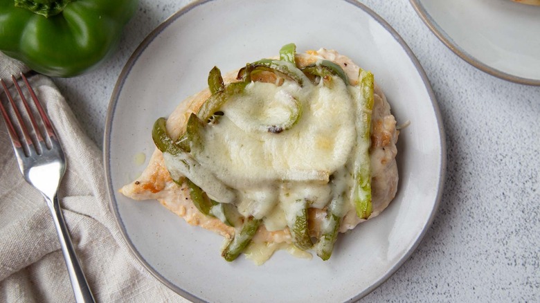 chicken with cheese and green peppers on a white plate