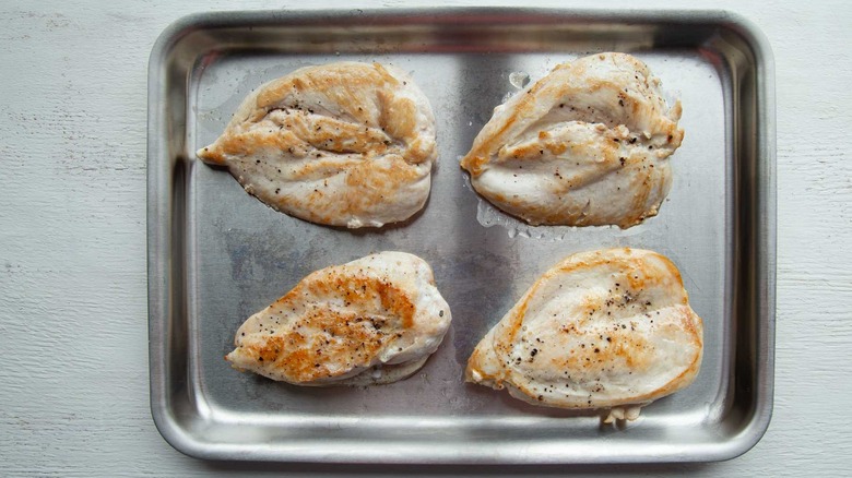 cooked chicken breasts in a baking pan